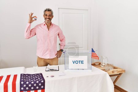 Foto de Hombre de pelo gris de mediana edad presidente de la mesa electoral con placa de voto en el colegio electoral - Imagen libre de derechos