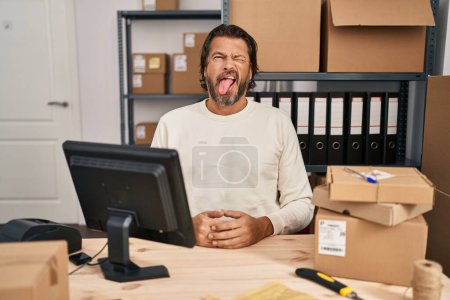 Photo for Handsome middle age man working at small business ecommerce sticking tongue out happy with funny expression. emotion concept. - Royalty Free Image