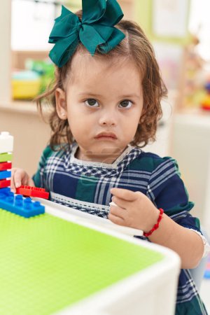 Photo for Adorable blonde toddler playing with construction blocks sitting on table at kindergarten - Royalty Free Image