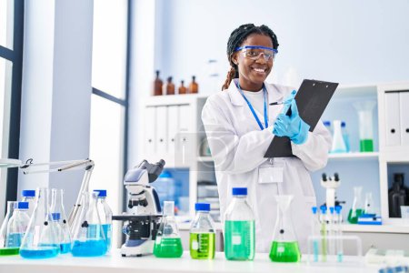 Téléchargez les photos : African american woman scientist writing report working at laboratory - en image libre de droit