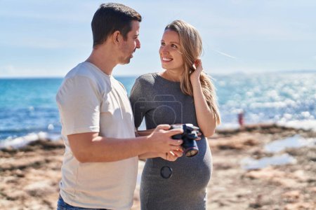 Photo for Man and woman couple expecting baby looking photo on professional camera at seaside - Royalty Free Image