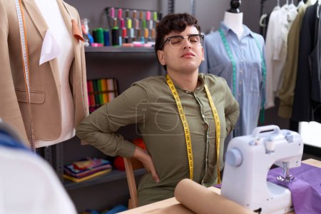 Foto de Non binary man tailor stressed using sewing machine at atelier - Imagen libre de derechos
