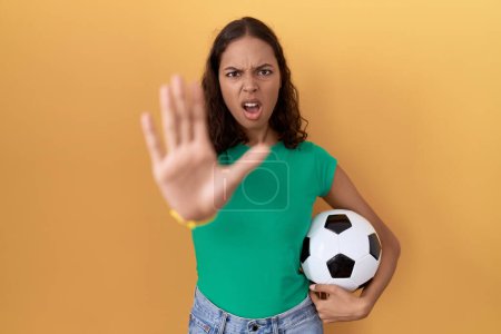 Photo for Young hispanic woman holding ball doing stop gesture with hands palms, angry and frustration expression - Royalty Free Image