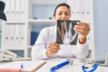 Téléchargez les photos : Middle age hispanic woman wearing doctor uniform holding xray at clinic - en image libre de droit