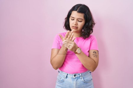 Photo for Young hispanic woman standing over pink background suffering pain on hands and fingers, arthritis inflammation - Royalty Free Image