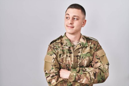 Foto de Young man wearing camouflage army uniform smiling looking to the side and staring away thinking. - Imagen libre de derechos