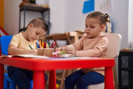 Foto de Two kids preschool students sitting on table drawing on paper at kindergarten - Imagen libre de derechos