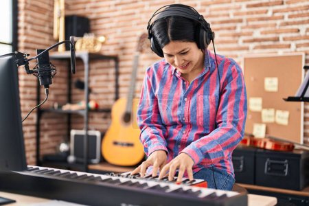 Téléchargez les photos : Young chinese woman musician playing piano keyboard at music studio - en image libre de droit