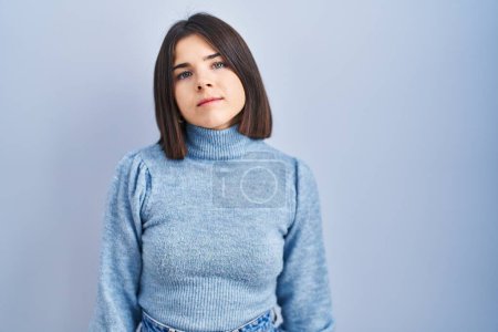 Photo for Young hispanic woman standing over blue background relaxed with serious expression on face. simple and natural looking at the camera. - Royalty Free Image
