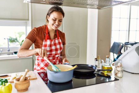 Photo for Young beautiful hispanic woman smiling confident cooking spaghetti at the kitchen - Royalty Free Image
