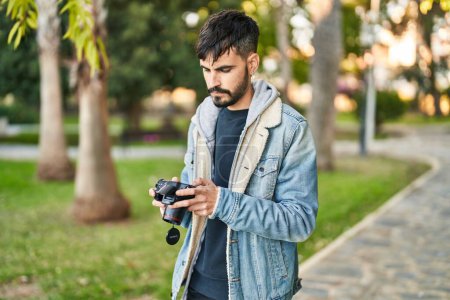 Foto de Young hispanic man using professional camera at park - Imagen libre de derechos