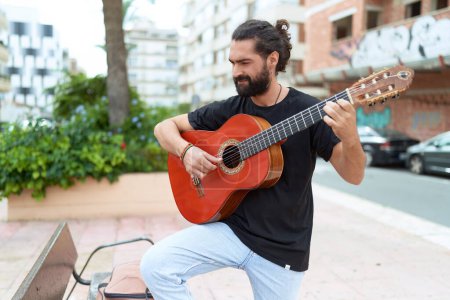 Foto de Young hispanic man musician playing classical guitar at park - Imagen libre de derechos