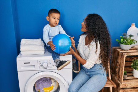 Photo for Mother and son playing with ball waiting for washing machine at laundry room - Royalty Free Image