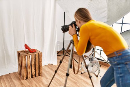 Foto de Young caucasian woman photographer making photo to high heel shoe at photography studio - Imagen libre de derechos