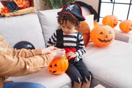 Téléchargez les photos : Adorable hispanic boy having halloween party holding pumpkin basket at home - en image libre de droit