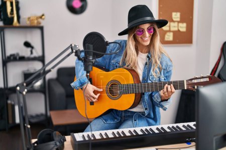 Téléchargez les photos : Young woman musician smiling confident playing classical guitar at music studio - en image libre de droit