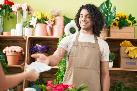 Photo for Young latin man florist holding dollars of client at flower shop - Royalty Free Image