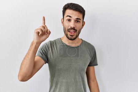 Photo for Young hispanic man with beard wearing casual t shirt over white background pointing finger up with successful idea. exited and happy. number one. - Royalty Free Image
