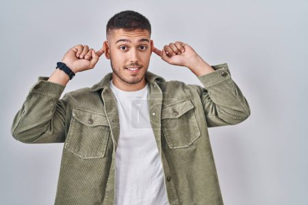 Photo for Young hispanic man standing over isolated background smiling pulling ears with fingers, funny gesture. audition problem - Royalty Free Image
