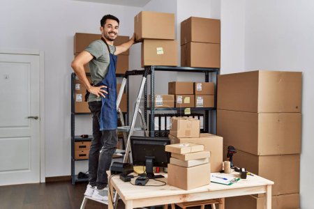 Téléchargez les photos : Jeune homme hispanique travailleur d'affaires debout sur l'échelle tenant paquet à l'entrepôt - en image libre de droit
