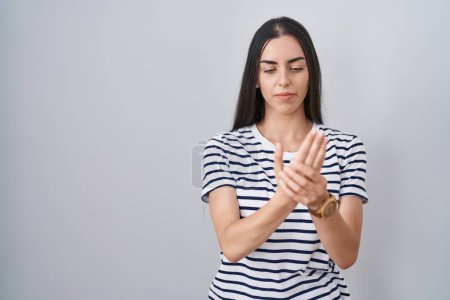 Photo for Young brunette woman wearing striped t shirt suffering pain on hands and fingers, arthritis inflammation - Royalty Free Image
