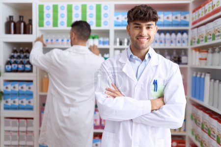 Foto de Two hispanic men pharmacists smiling confident standing with arms crossed gesture at pharmacy - Imagen libre de derechos