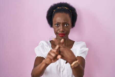 Téléchargez les photos : Femme africaine avec les cheveux bouclés debout sur fond rose expression de rejet en croisant les doigts faisant signe négatif - en image libre de droit