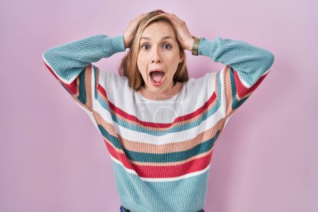 Téléchargez les photos : Young blonde woman standing over pink background crazy and scared with hands on head, afraid and surprised of shock with open mouth - en image libre de droit