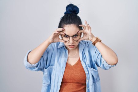 Foto de Young modern girl with blue hair standing over white background trying to open eyes with fingers, sleepy and tired for morning fatigue - Imagen libre de derechos