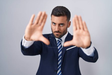 Photo for Handsome hispanic man wearing suit and tie doing frame using hands palms and fingers, camera perspective - Royalty Free Image