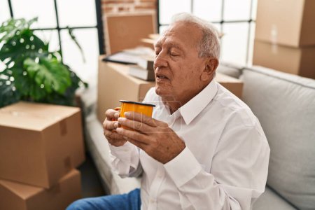 Foto de Hombre mayor sonriendo confiado bebiendo café en casa nueva - Imagen libre de derechos
