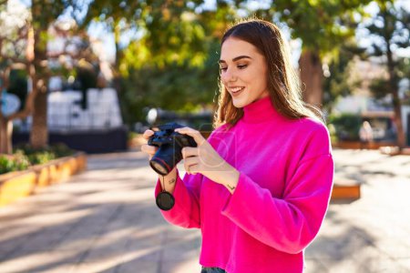Foto de Mujer joven sonriendo confiado utilizando la cámara profesional en el parque - Imagen libre de derechos
