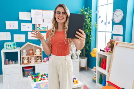 Photo for Young blonde woman teacher having video call standing at kindergarten - Royalty Free Image