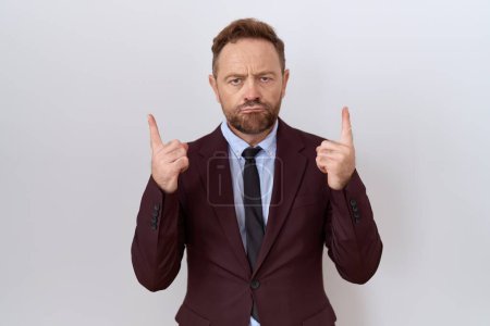 Photo for Middle age business man with beard wearing suit and tie pointing up looking sad and upset, indicating direction with fingers, unhappy and depressed. - Royalty Free Image