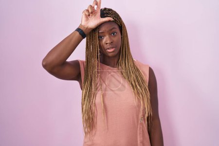 Téléchargez les photos : Femme afro-américaine avec des cheveux tressés debout sur fond rose se moquant des gens avec les doigts sur le front faisant geste de perdant moquerie et insultant. - en image libre de droit