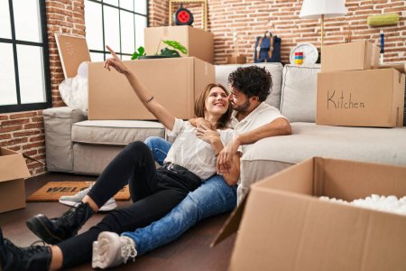 Téléchargez les photos : Homme et femme couple souriant confiant se serrant dans leurs bras à la nouvelle maison - en image libre de droit