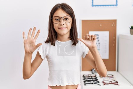 Téléchargez les photos : Young hispanic girl wearing glasses showing and pointing up with fingers number six while smiling confident and happy. - en image libre de droit