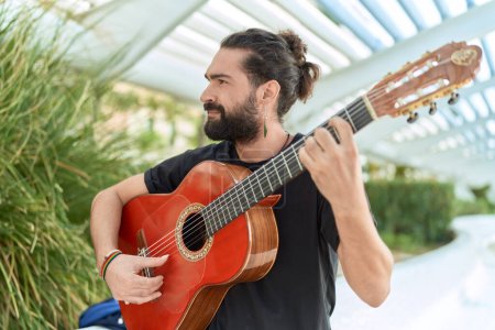 Téléchargez les photos : Jeune musicien hispanique jouant de la guitare classique au parc - en image libre de droit