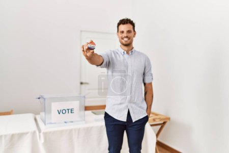 Photo for Young hispanic man smiling confident holding i voted badge at electoral college - Royalty Free Image