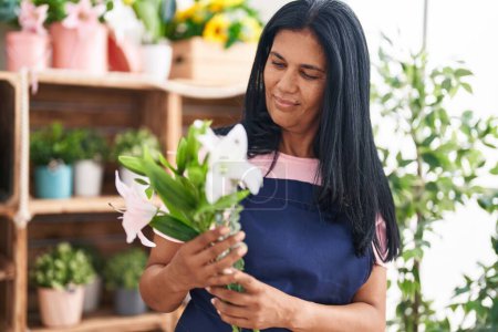Photo for Middle age hispanic woman florist holding bouquet of flowers at florist - Royalty Free Image