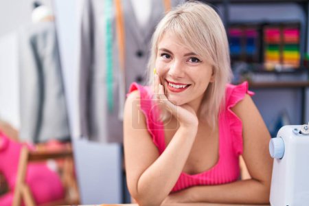 Foto de Young blonde woman tailor smiling confident sitting on table at gaming room - Imagen libre de derechos