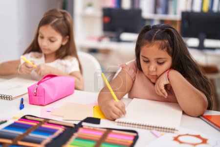 Téléchargez les photos : Deux enfants d'âge préscolaire assis sur la table dessinent sur du papier en classe - en image libre de droit