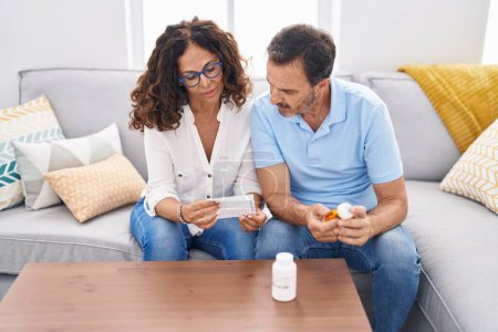 Téléchargez les photos : Homme et femme couple tenant des pilules lecture prescription à la maison - en image libre de droit