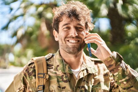 Téléchargez les photos : Jeune soldat de l'armée parle sur smartphone au parc - en image libre de droit