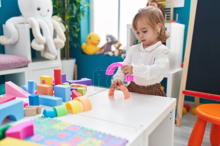 Foto de Adorable chica rubia jugando con juguetes de pie en el jardín de infantes - Imagen libre de derechos