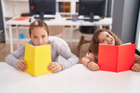 Foto de Dos niños estudiantes leyendo libro estudiando en el aula - Imagen libre de derechos