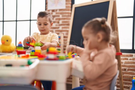 Photo for Two kids playing with construction blocks sitting on table at kindergarten - Royalty Free Image