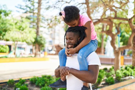 Foto de Father and daughter smiling confident holding girl on shoulders at park - Imagen libre de derechos