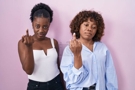 Photo for Two african women standing over pink background showing middle finger, impolite and rude fuck off expression - Royalty Free Image