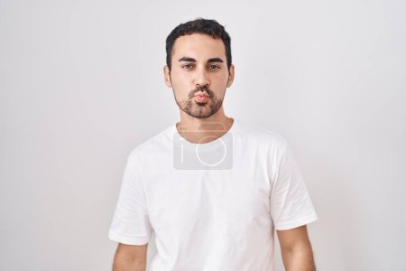 Photo for Handsome hispanic man standing over white background looking at the camera blowing a kiss on air being lovely and sexy. love expression. - Royalty Free Image
